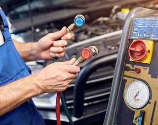 Mechanic holds a set of high-pressure pipes for filling the car's air conditioning system