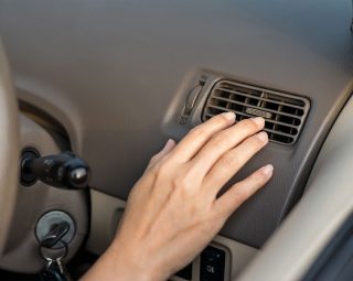 Close up of hand woman checking the air conditioner in her car