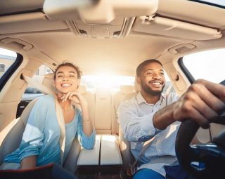 Enjoying travel. Excited african couple driving car and smiling, copy space