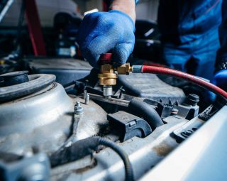 hands of car mechanic connects air conditioning system in auto service