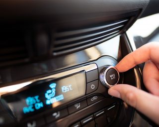 Man turning on car air conditioning system