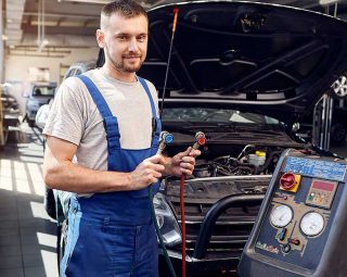 Mechanic holds a set of high-pressure pipes for filling the car's air conditioning system.