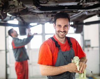 Profecional car mechanic changing motor oil at maintenance repair service station