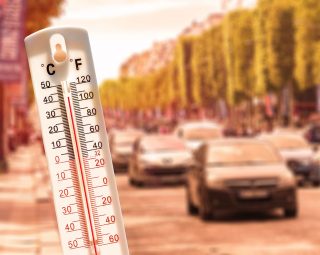 Thermometer in front of cars and traffic during heatwave